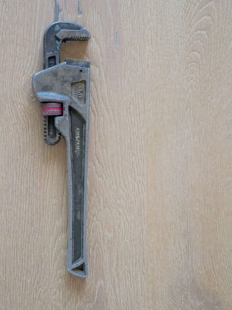 Adjustable plumber wrench resting on a timber surface