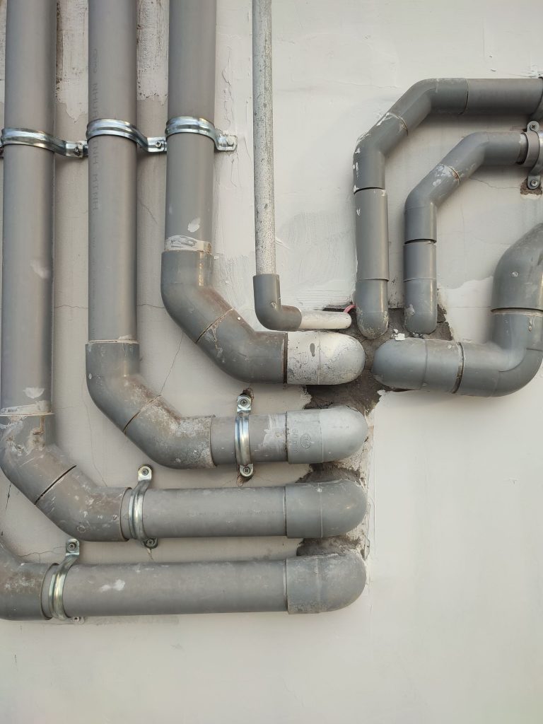 Grey PVC drainage pipes and bends fixed to an exterior wall