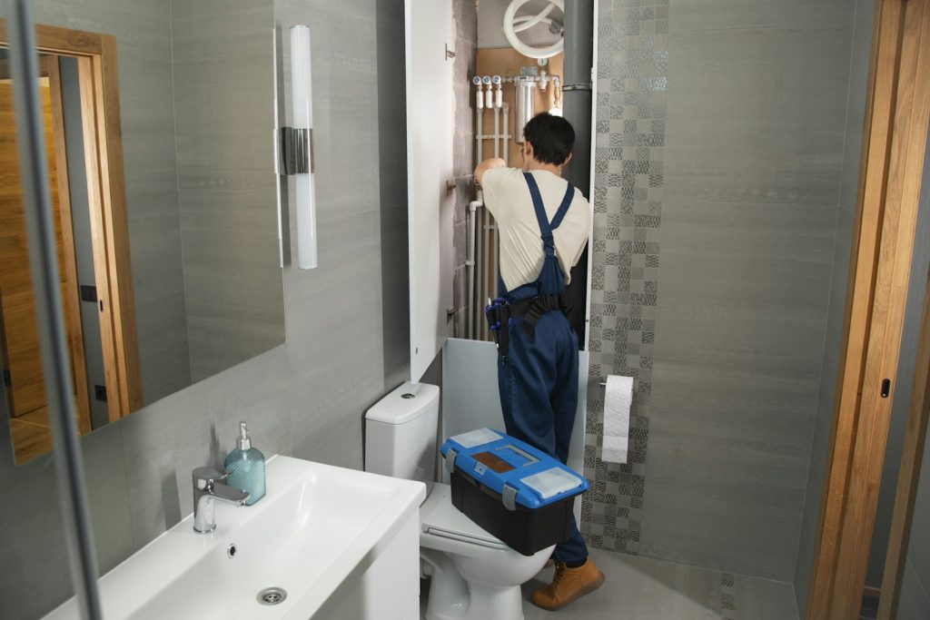 Plumber working on the water supply behind a bathroom washbasin