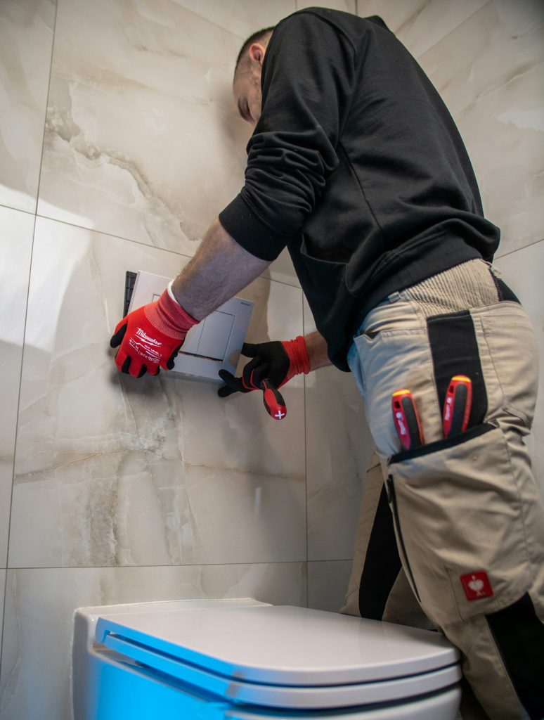 Plumber wearing gloves repairing a toilet